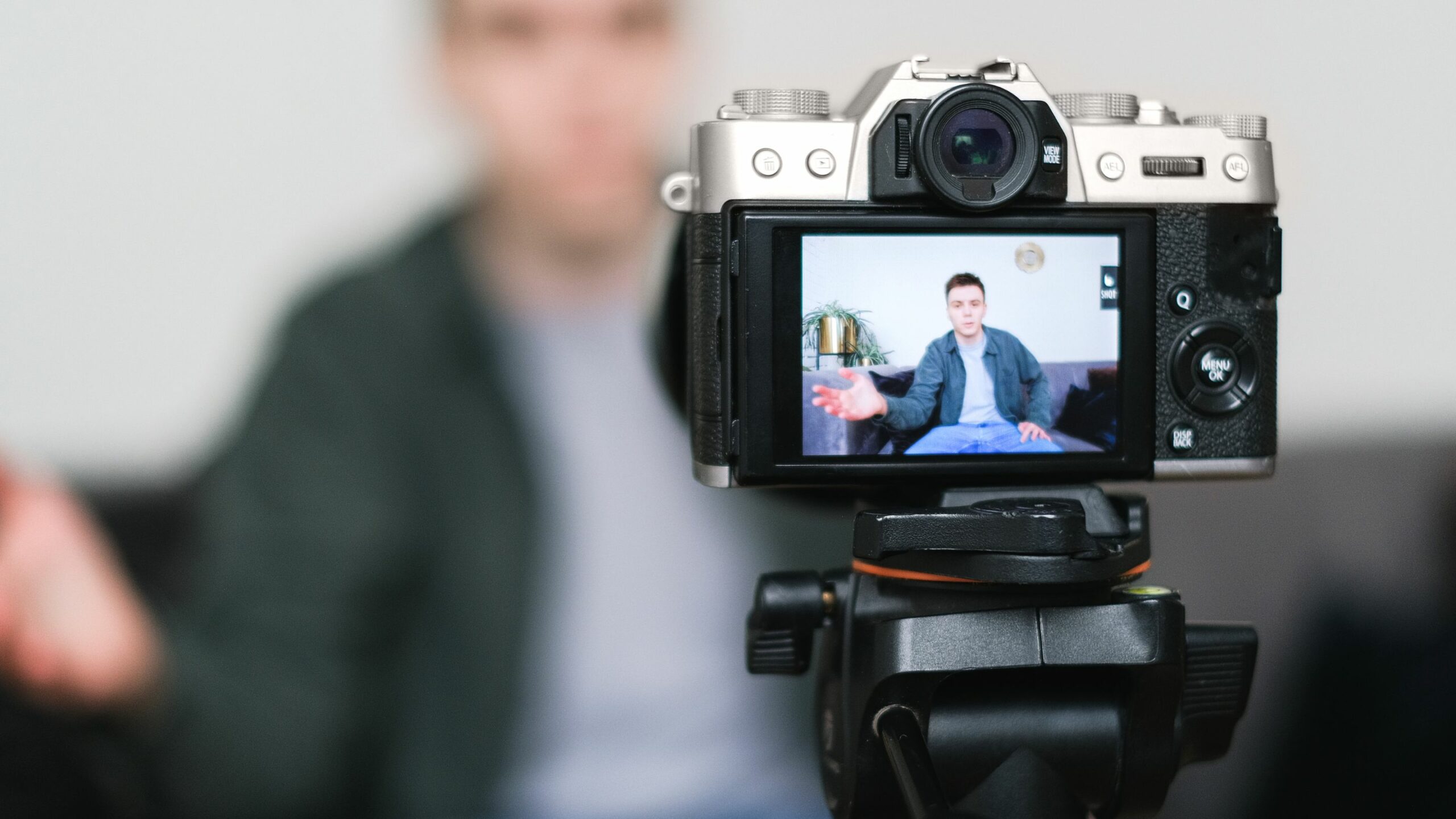 man sitting on couch in front of camera filming himself speaking